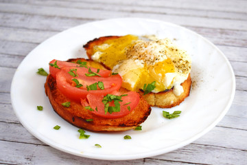 Crispy toast, scrambled eggs and tomatoes on a white plate for Breakfast.
