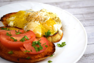 Crispy toast, scrambled eggs and tomatoes on a white plate for Breakfast.