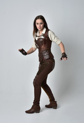 full length portrait of brunette  girl wearing brown leather steampunk outfit. standing pose on...
