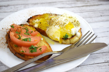 Crispy toast, scrambled eggs and tomatoes on a white plate for Breakfast.