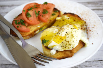 Crispy toast, scrambled eggs and tomatoes on a white plate for Breakfast.