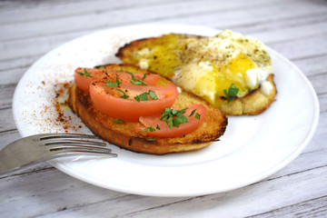 Crispy toast, scrambled eggs and tomatoes on a white plate for Breakfast.