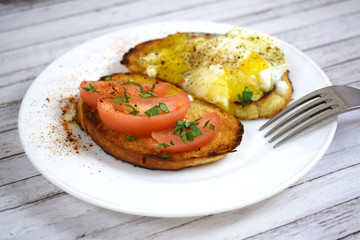 Crispy toast, scrambled eggs and tomatoes on a white plate for Breakfast.