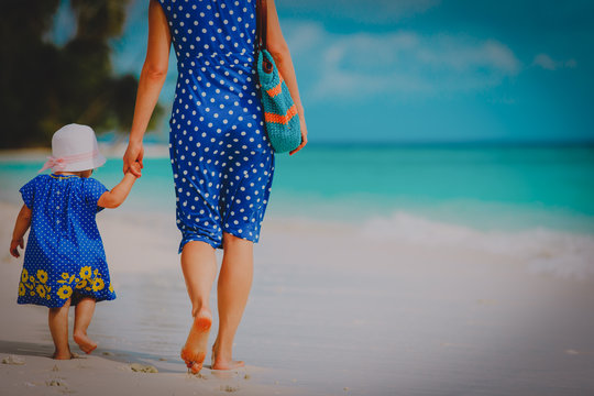 Mother And Cute Little Daughter Walking On Beach