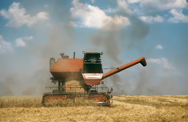 vintage retro old combine harvester at work gathering wheat, autumn harvest, sunny day