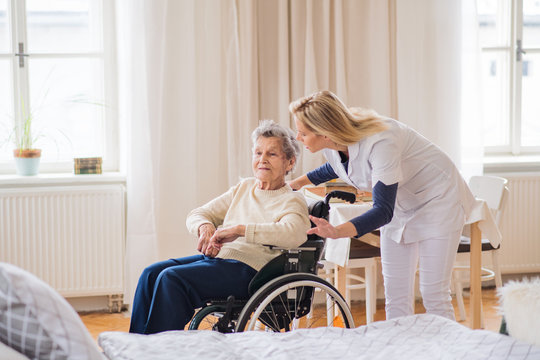 A health visitor talking to a senior woman in wheelchair at home.