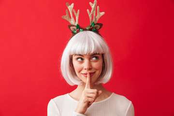 Cute woman isolated over red wall background wearing deer ears costume carnival showing silence...