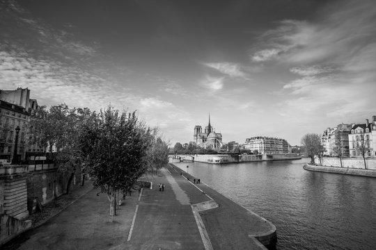 Cathedral of Notre Dame de Paris sunny autumn afternoon. Embankment of the Seine. The natives and tourists take a walk and relax in warm weather. Blurred unrecognizable faces. BW photo. Paris. France.