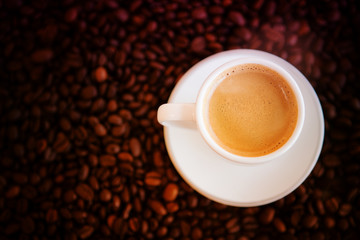 cup with freshly brewed coffee and whole coffee beans