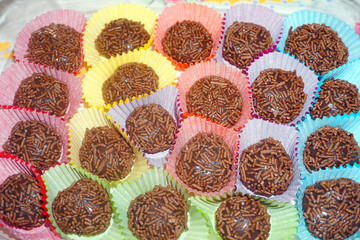 Delicious Brazilian chocolate ball Brigadier made from condensed milk and chocolate hail coating in colorful paper tray Christmas treat sweet dessert on white plate