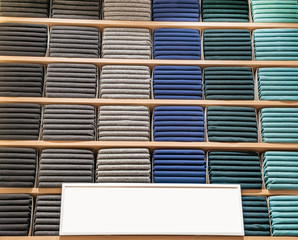 Clothes displayed in store. Copy spase for text. Lot warm sweaters of different color are neatly stacked in a row on the store shelves. Piles of multicolored knitted woolen clothing. T-shirt on shelve