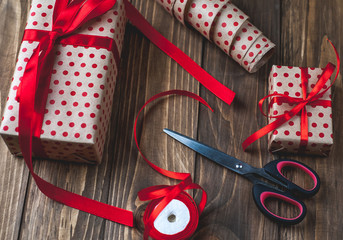 making gifts with a red ribbon on a wooden table