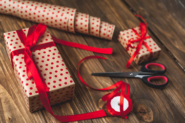 making gifts with a red ribbon on a wooden table