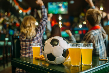 Ball and beer on the table in sports bar