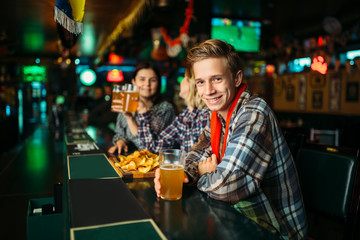 Fans with glasses of beer at counter in sports bar