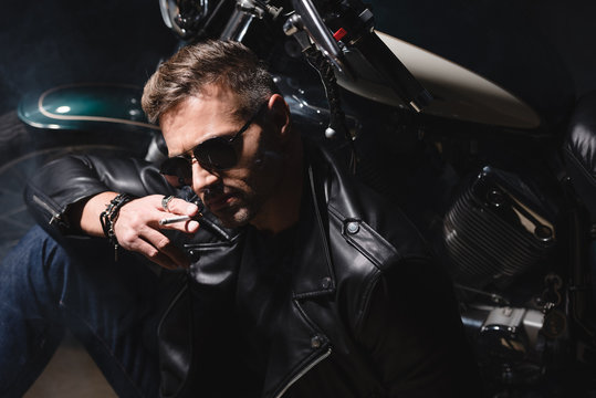 handsome guy in sunglasses sitting by motorcycle in garage © LIGHTFIELD STUDIOS