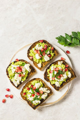 Smashed avocado, goat cheese, pomegranate salsa bruschetta on cutting board. Top view, space for text.