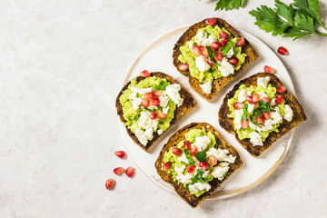 Smashed avocado, goat cheese, pomegranate salsa bruschetta on cutting board. Top view, space for text.