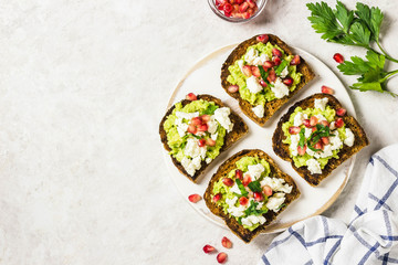 Smashed avocado, goat cheese, pomegranate salsa bruschetta on cutting board. Top view, space for text.