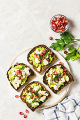 Smashed avocado, goat cheese, pomegranate salsa bruschetta on cutting board. Top view, space for text.