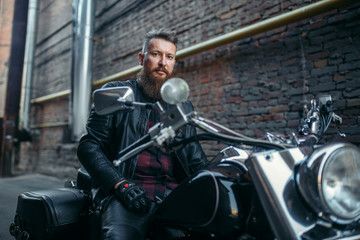 Fototapeta na wymiar Biker in leather jacket on classical chopper