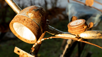 Old bike with front lights and rust with Morning sun.