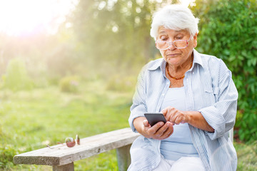 old woman dials the number talking on the phone, smartphone, smiling, call the children