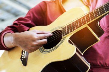 Fototapeta premium Close-up women playing acoustic guitar on walking street.