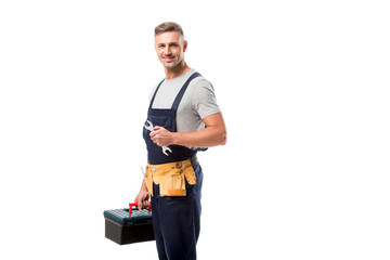 handsome worker holding tool box, wrench and looking at camera isolated on white
