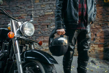 Fototapeta premium Biker in leather jacket with helmet in hand