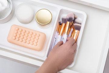 Woman hands taking cosmetic brush, Inside of opened driwes