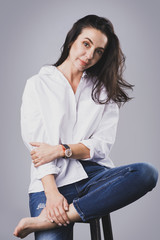 Beautiful middle aged woman wearing white shirt and jeans in photo studio