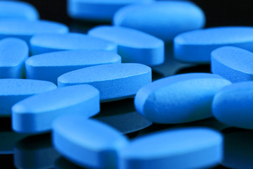 blue pills on a black background - obrazy, fototapety, plakaty