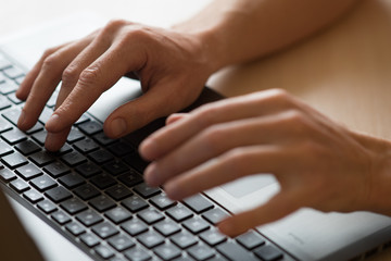 Men hands typing on a keyboard of laptop.