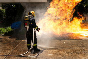 Obraz premium Firefighters with extinguisher spraying high pressure water to fighting the fire flame in an emergency situation.