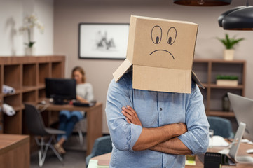 Business man wearing sad face cardboard