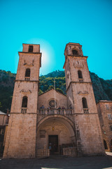 Fototapeta na wymiar KOTOR, MONTENEGRO - July 20, 2018 old church with two towers and tourists on it