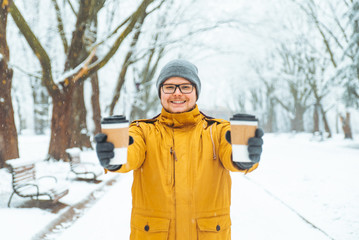 man bring coffee to go for friends in snowed city park