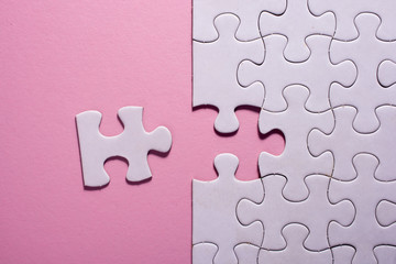 Incomplete white jigsaw puzzle pieces on pink background