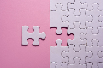Incomplete white jigsaw puzzle pieces on pink background