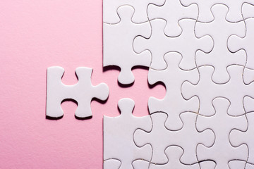 Incomplete white jigsaw puzzle pieces on pink background