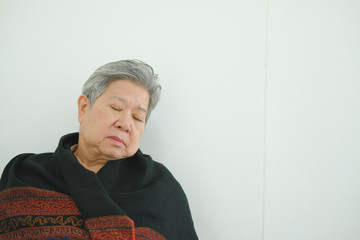 elder woman taking a nap. asian elderly senior napping sleeping near white wall