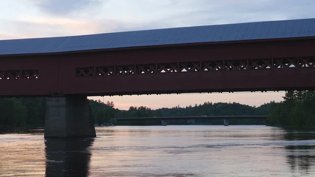 Iconic wooden covered bridge at dusk in Wakefield, Quebec. Route 366 or Chemin Edelweiss in the background.