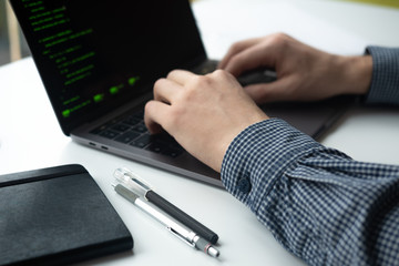 Man working on his computer. Man's hands with laptop.