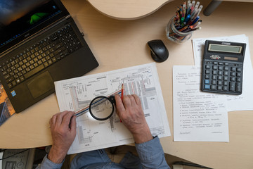 an architect, a white-haired man, 60 years old, works with project documentation at the table