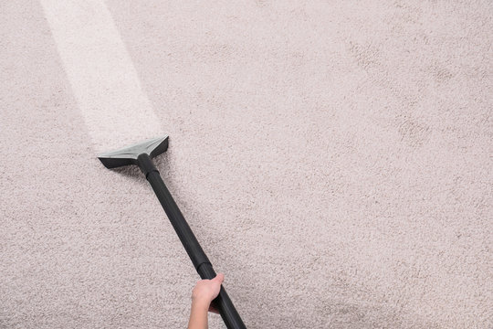 Woman removing dirt from carpet with vacuum cleaner in room, top view