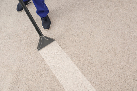 Man removing dirt from carpet with professional vacuum cleaner in room, top view
