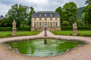 The abbey garden in Echternach - the oldest town in Luxembourg, with a fountain and the building of the Orangery on an overcast May day