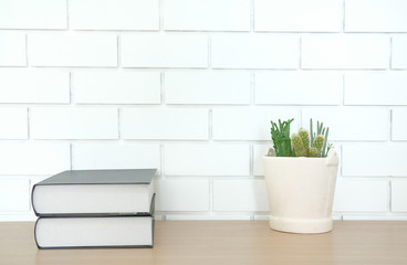 book on wooden desk near white brick wall. office workplace top view