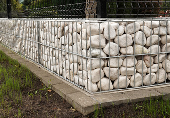 Gabion. New garden fence using metal baskets filled with white pebbles.